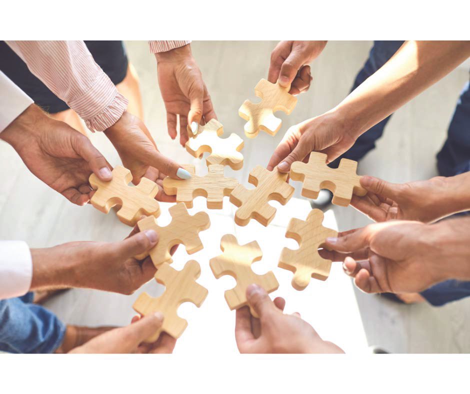 hands in a circle holding neutral coloured puzzle pieces